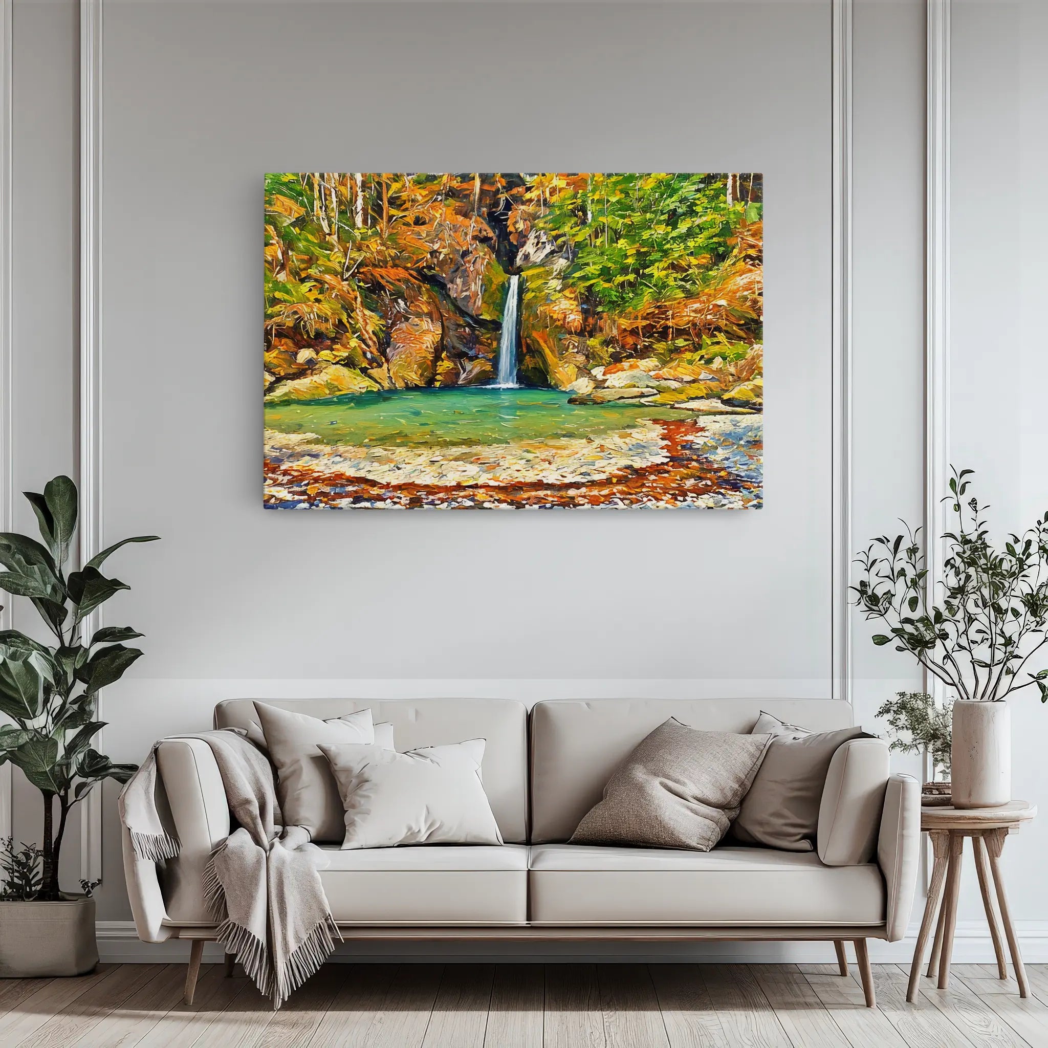 A living room with a beige sofa, decorative pillows, and a large painting of a waterfall surrounded by autumn foliage on the wall.