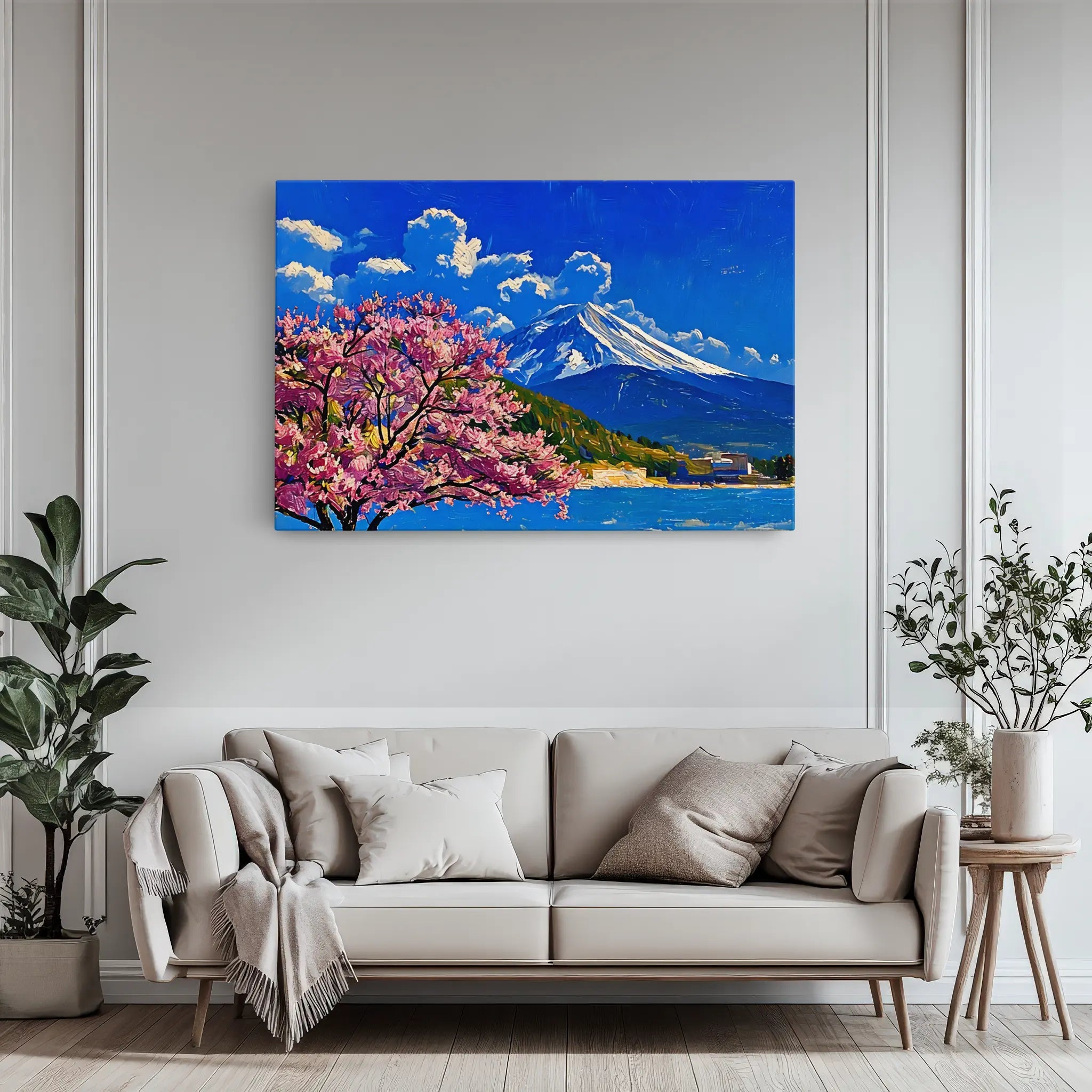 A modern living room with a beige sofa, decorative pillows, and a large painting of a mountain and cherry blossoms on the wall.
