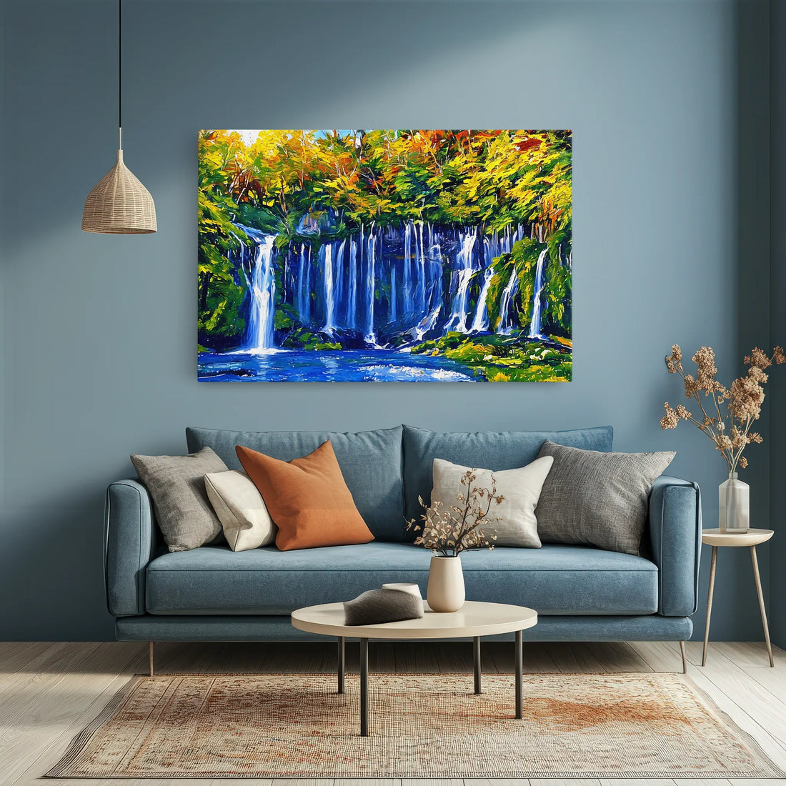 A cozy living room with a blue sofa, colorful cushions, a round coffee table, and a vibrant waterfall painting on the wall.